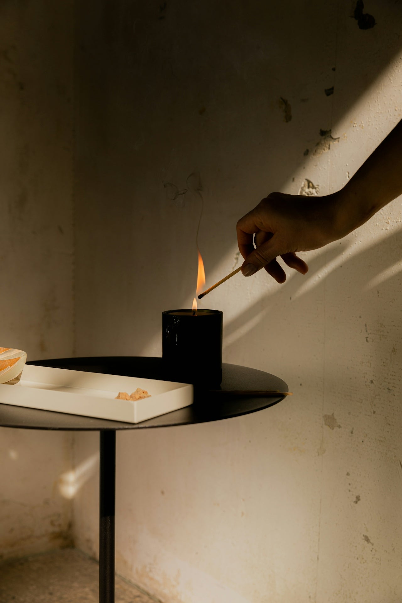 A person lighting a candle in a sunlight room.